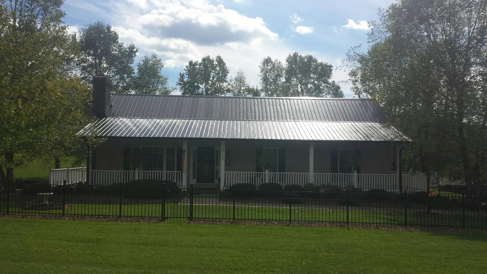 Gray metal roof on a brick ranch with a full width front porch — Gutter Guard Installation work by our crew in Custer
